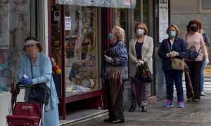 12/05/2020.- Varias mujeres con mascarillas hacen cola ante una mercería en el barrio de Triana de Sevilla, hoy martes en el segundo día de la fase 1 de desescalada en la que diferentes actividades han podido retomar su actividad desde que se inició el es