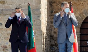 01/07/2020.- El presidente del Gobierno, Pedro Sánchez (i) y el rey Felipe VI (d) se ponen las mascarillas antes de la foto oficial en la explana del castillo de Elvas durante el acto oficial de la reapertura, tras tres meses y medio cerradas por el coro