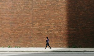 Una mujer camina junto a un muro de ladrillo.- Greg Shield / Unsplash