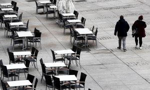 22/10/2020.- Dos personas caminan por la Plaza del Castillo de Pamplona que hoy jueves presenta un inusual aspecto con las terrazas de los bares vacías en una jornada en la que cientos de pamploneses salen este día "Juevintxo", para compartir en la calle