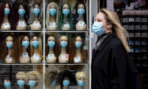 Una mujer con mascarilla pasa frente a un escaparate en París.