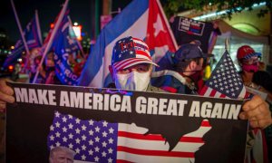 Simpatizantes de Donald Trump sostienen pancartas y banderas a favor del mandatario mientras esperan los resultados de las elecciones en el icónico café Versailles de la Calle Ocho en Miami, Florida.