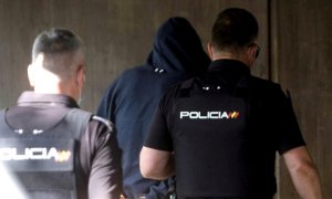 Agentes de la Policía Nacional conducen a uno de los cuatro detenidos por el homicidio de Samuel este viernes al interior de los juzgados de la Coruña.