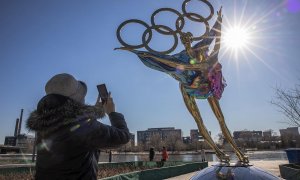 Una mujer fotografía una escultura de una pareja de patinaje artístico con motivo de los Juegos Olímpicos de Invierno 2022 en el parque industrial Shougang en Pekín.