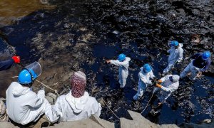 Varios operarios trabajan en labores de limpieza del petróleo derramado en las costas peruanas por la refinería de La Pampilla operada por Repsol.