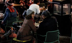 Dos personas en una terraza en la Plaza de Santa Ana para celebrar la llegada de la Nochebuena, a 24 de diciembre de 2021, en Madrid (España). A pesar de las nuevas restricciones, como el uso de la mascarilla en exteriores, que entra en vigor hoy, varias