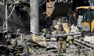 24/03/2022 Un militar ucraniano carga un fragmento de misil mientras sale de un edificio bombardeado de Kiev, a 24 de marzo