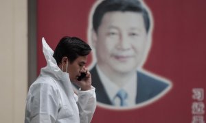 Un hombre con equipo de protección habla por teléfono en la calle, frente al cartel del presidente chino Xi Jinping, en medio del bloqueo de Covid-19 en Shanghái, China, el 23 de mayo de 2022.