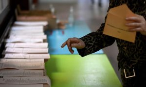 Una mujer recoge una papeleta en un colegio electoral en Madrid durante las elecciones regionales de Madrid el 4 de mayo de 2021.- AFP