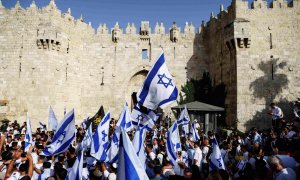 Los israelíes bailan y cantan mientras sostienen banderas nacionales israelíes junto a la puerta de Damasco en la ciudad vieja de Jerusalén.