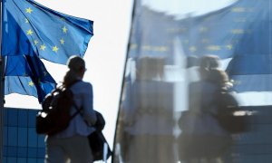 Una mujer pasa junto a las banderas de la UE situadas en el extrerior de la sede de la Comisión Europea, en Bruselas. AFP/Kenzo Tribouillard