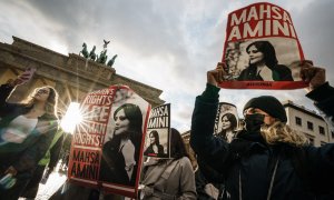 28/09/2022-Manifestantes sostienen pancartas con una imagen de Mahsa Amini durante una concentración en reacción a su muerte, frente a la Puerta de Brandenburgo en Berlín, Alemania, 28 de septiembre de 2022.