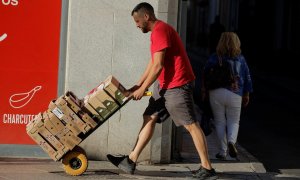 Un repartidor traslada una carretilla con productos de un supermercado, en la localidad malagueña de Ronda.  REUTERS/Jon Nazca