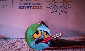 Una activista sujeta una pancarta con la imagen de la  imagen de la tierra entrando en ebullición por la crisis climática en la Cumbre del Clima de Sharm el Sheikh (COP27).