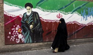 Una mujer junto a un mural con la bandera iraní y el ayatolá Ruholá Jomeini en Teherán (Irán). Imagen de Archivo.