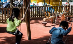 Dos niños juegan junto a contenedores llenos de basura, a 3 de mayo de 2023, en Figueres, Girona, Catalunya.