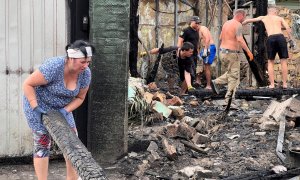 Residentes locales retiran escombros de edificios dañados por un ataque con misiles rusos en Tarasivka.