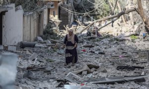 Una mujer palestina recorre una calle de la ciudad de Gaza cubierta de escombros por los bombardeos de la aviación israelí, que se mantienen por quinto día consecutivo.