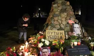 Una mujer se agacha para encender una vela, mientras la gente asiste a un evento conmemorativo, después de la muerte del líder de la oposición rusa Alexei Navalny en Vilna, Lituania.