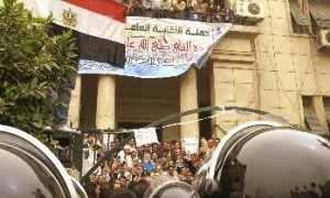 Un manifestante muestra una bandera egipcia a los policías antidisturbios, durante una protesta celebrada en el Sindicato de Abogados de El Cairo en contra del Gobierno egipcio y el encarecimiento de los precios en el país.