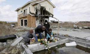 Una familia coloca flores y ora por sus parientes víctimas del terremoto y el tsunami del 11 de marzo de 2011 en el país. EFE/KIMIMASA MAYAMA