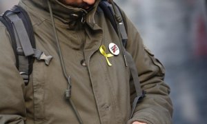 Una persona amb un llaç groc i una xapa que demana la llibertat per als presos polítics. Europa Press.