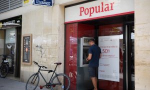 Un hombre saca dinero de un cajero automático del Banco Popular, en la localidad barcelonesa de Vilanova i la Geltru, en una foto del 7 de junio de 2017, el día que se anunció la resolución de la entidad. AFP/Lluis Gené