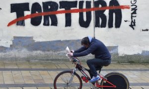 Un hombre pasea en bicicleta por un graffiti contra la tortura en el pueblo vasco de Agurain / Salvatierra. ANDER GILLENEA / AFP