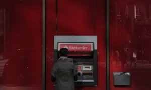 Una mujer utiliza un cajero automático en una oficina del Banco Santander en el centro de Londres. AFP/Carl Court