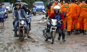 Residentes locales con sus scooters en una carretera embarrada después de un tsunami en el Estrecho de Sunda en Pandeglang, Banten, Indonesia.- EFE/EPA/ADI WEDA