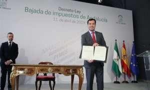 El presidente Juanma Moreno muestra el decreto-ley de rebaja fiscal que acaba de firmar junto a su consejero de Hacienda, Juan Bravo.