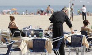 Un camarero atiende las mesas de un restaurante junto a la playa. EFE
