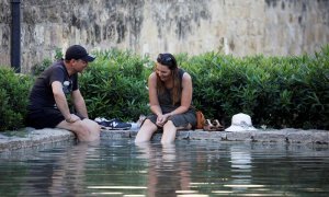 Unos turistas se refrescan en una de las fuentes de Córdoba. EFE/Salas