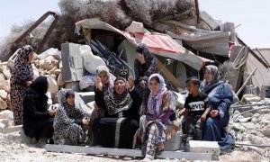 17/06/2019.- Una familia palestina permanece sentada cerca de los escombros de su casa tras ser demolida por las fuerzas israelíes, este lunes, en Yatta, al sur de Hebrón. El ejército israelí destruye las casas de aquellos palestinos que no tienen los per