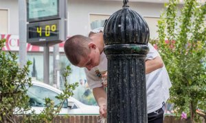 Un joven se refresca en una fuente de Murcia este medio día junto a un termómetro que marca 40º centígrados. EFE/Marcial Guillén