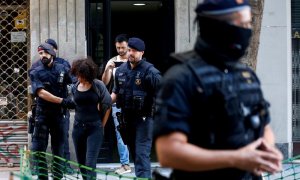 Mossos d'Esquadra trasladan a una persona detenida tras un operativo conjunto con la Guardia Urbana para desmantelar pisos convertidos en puntos de venta de droga en el barrio de Sant Antoni de L'Eixample y en el distrito de Sants-Montjuïc de Barcelona. E