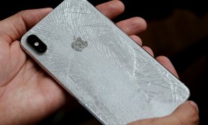 Un hombre sujeta un Smartphone de Apple, cuya carcasa posterior está agrietada./ REUTERS