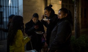 Una madre, solicitante de asilo colombiana, cena gracias a la ayuda de la Red de Solidad Popular, junto a sus tres hijos menores, en la puerta del Samur Social de Madrid-. JAIRO VARGAS