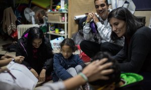 Julio Aponte junto a su mujer Margareth Jiménez (izquierda), juegan con sus hijos y la abogada Patricia Fernández en la habitación de la parroquia San Carlos Borromeo de Entrevías, donde llevan casi cinco meses esperando un plaza en el sistema de asilo y