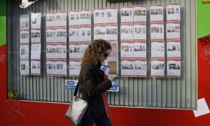 Una joven pasa por delante de una inmobiliaria con anuncios de casas en alquiler o en venta en el centro de Madrid. REUTERS/Andrea Comas