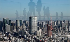 Los visitantes se reflejan en el vidrio acrílico de una plataforma del mirador en un edificio desde donde se observa el centro de  Tokio (Japón). EFE / EPA / KIMIMASA MAYAMA