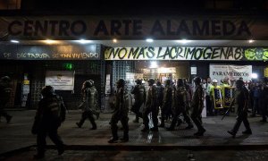 Un grupo de Fuerzas Especiales de Carabineros camina frente al cine Arte Alameda custodiado por voluntarios sanitarios el pasado viernes 13 de diciembre. /EFE