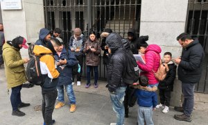 Varios solicitantes de asilo intentan reservar su cita previa de extranjería para acceder al sistema de acogida, en la puerta del Samur Social de Madrid.- RSP