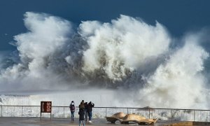 20/01/2020.- Varias personas observan las grandes olas en la playa de la Barceloneta, en Barcelona, este lunes, durante el fuerte temporal de Levante que azota Cataluña y que deja registros históricos de oleaje, viento y nieve, como la ola de 12 metros re