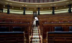 Una empleada de la Cámara limpia el hemiciclo del Congreso vacío