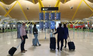 Varios pasajeros miran los paneles informativos de los vuelos en el aeropuerto de Barajas, en Madrid.. REUTERS/Susana Vera