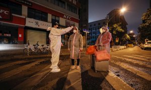 Un voluntario toma la temperatura a una mujer embaraza en la ciudad china de Wuhan. - EFE