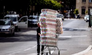 Un trabajador transporta numerosos rollos de papel higiénico en un carro de la compra dirección a un comercio en el centro de Málaga. - EFE