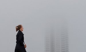 Una persona pasa junto a un edificio envuelto en niebla en Valencia. EFE