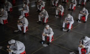 Trabajadores de una fábrica de Wuhan (China) comen sentados a un metro y medio de distancia. La ciudad comienza poco a poco a recuperar la normalidad. /EFE